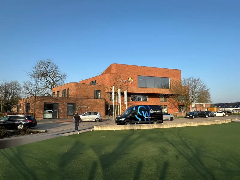 Bedrijfsbus van Westendorp voor het gebouw van Lumen in Enschede
